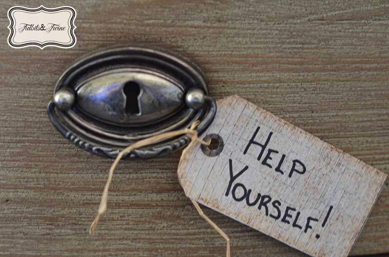 closeup on antique pull ring drawer pull with a tag tied to it that says help yourself