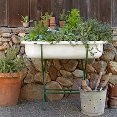 vintage baby bathtub used as a garden planter next to a rock wall