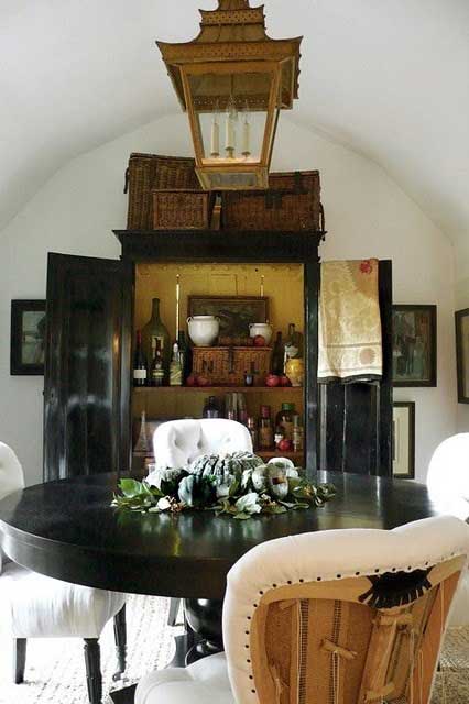 Black armoire used as a bar with round table and rustic lantern hanging above