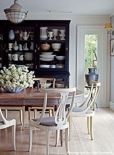 Dining room with black buffet filled with white dishes and oval dining table