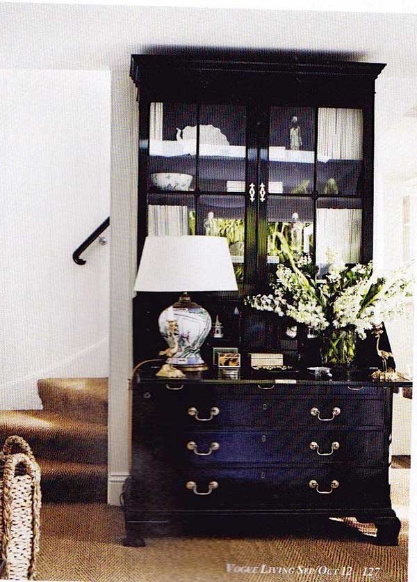 Large black secretary desk with lamp and white flowers on top and textured rug