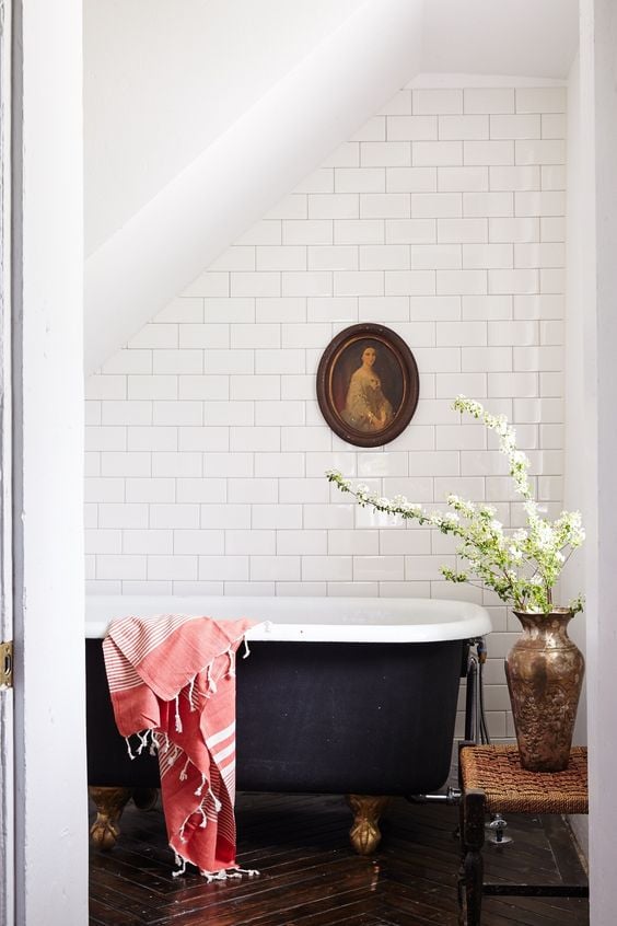 bathroom with black clawfoot tub and white tile surround