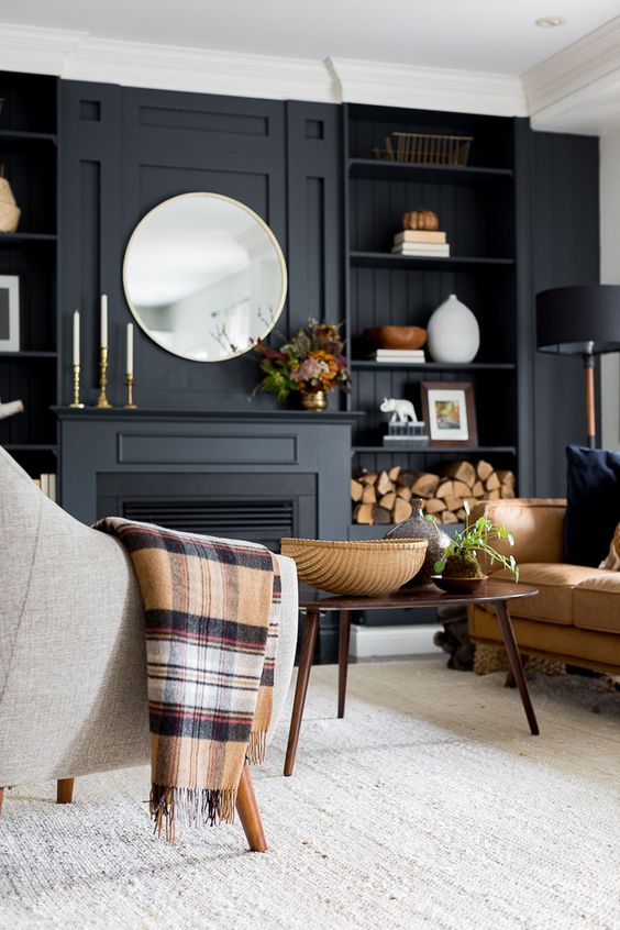 Living room with black accent wall with black fireplace and built-ins on either side with leather sofa