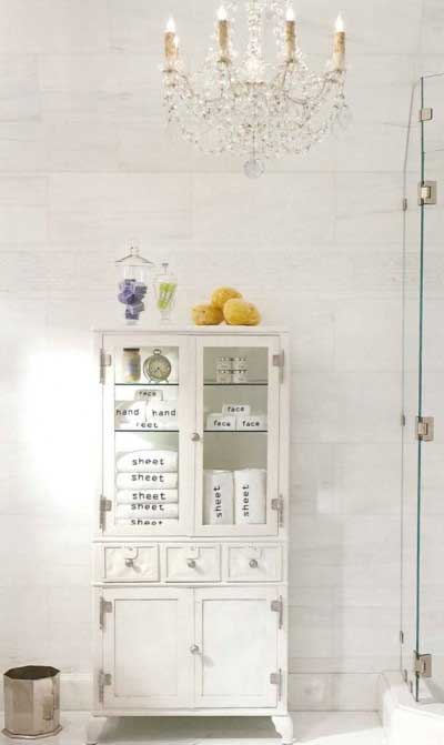 antique white metal medical cabinet in a bathroom holding towels sponges and more