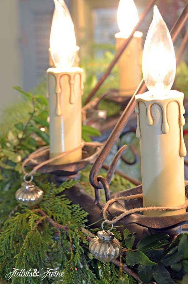 french chandelier with candles decorated for christmas with greenery and ornaments