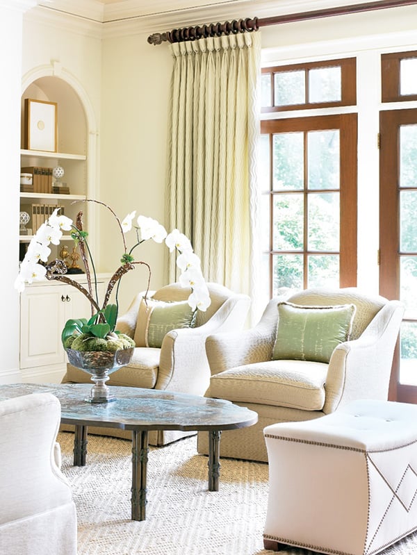 Living room with beige swivel chairs and large orchid arrangement on a dark wood coffee table