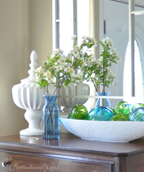 Small chest of drawers with blue and green seaglass in a white dish and mirror above