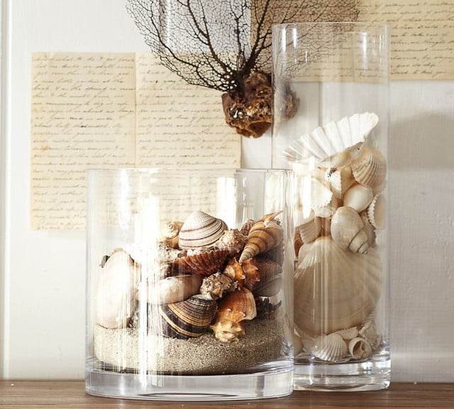 Closeup of two glass vases filled with sand and seashells