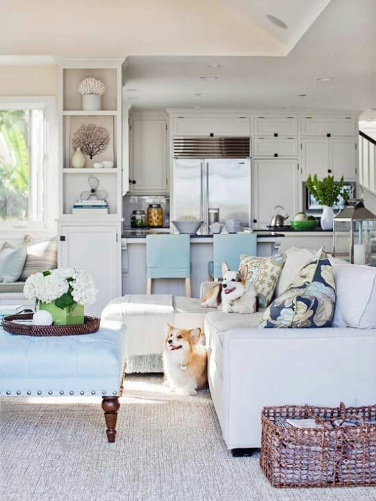 White family room and kitchen with pops of blue and baby blue tufted ottoman