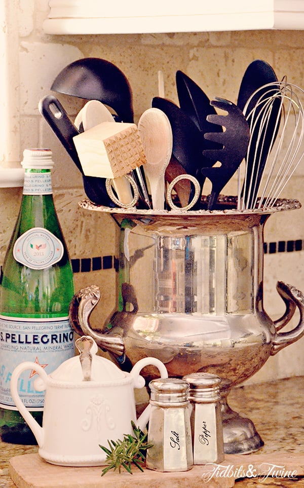 Antique silver champagne bucket holding kitchen utensils with silver salt and pepper shakers