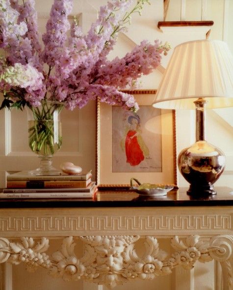 Closeup of entry table with a gold lamp and large vase of tall purple flowers