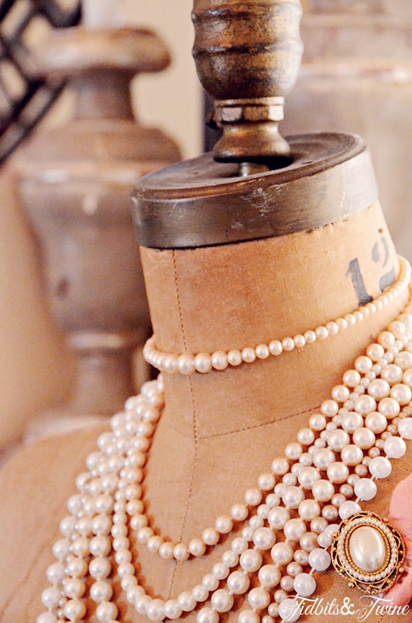 Closeup of vintage dress form with pearl necklaces and a pearl broach