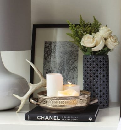 {A tarnished silver bowl and a single antler is paired with a sleek lamp and modern vase. Image via Rue Magazine.}