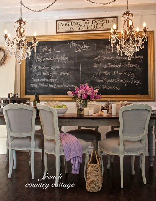 French dining room with two chandeliers and large chalkboard on the wall