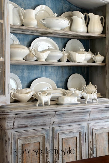 White ironstone collection in a dining hutch with blue inside