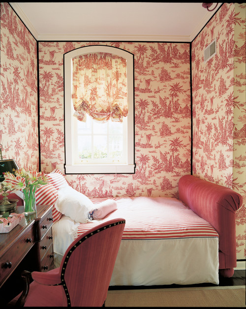 red toile wallpaper in a bedroom with red upholstered bed with red and white striped bedding