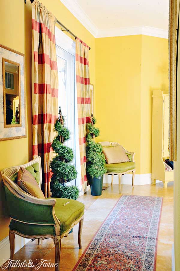 Yellow hallway in european home with green accent chairs and plaid curtains