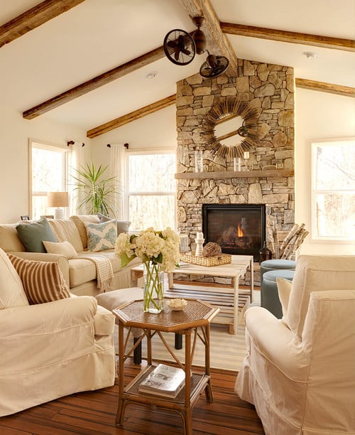 A beach style sunroom with white slipcovered furniture and light blue accepts and stone fireplace