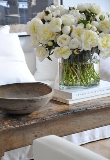 Huge vase of white flowers on top of a rustic wood coffee table