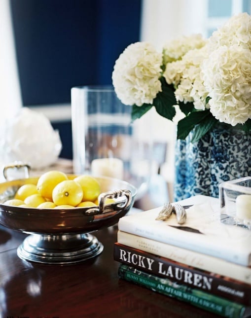 Closeup of coffee table with a bowl of lemons stack of books and hydrangeas