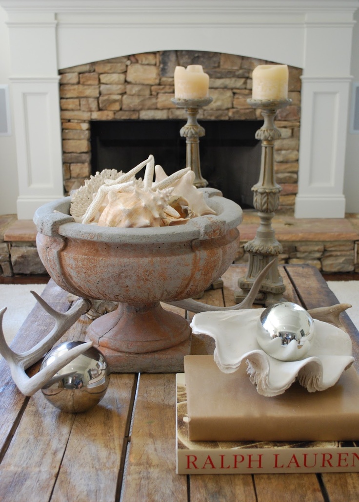 Industrial coffee table with urn holding seashell collection and two large candlesticks