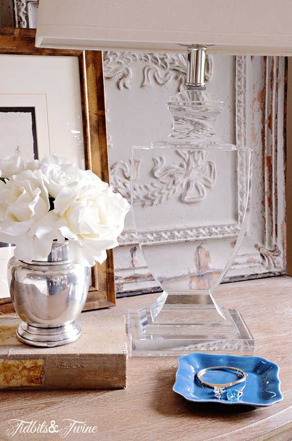 French nightstand with french-wired crystal lamp and silver vase of roses