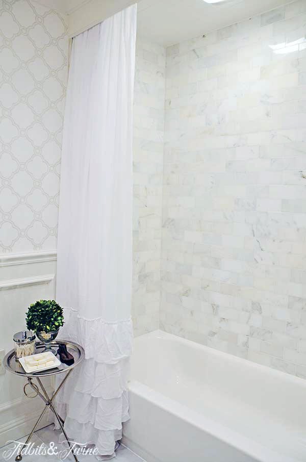 tub shower combo with marble subway tile and white ruffle shower curtain