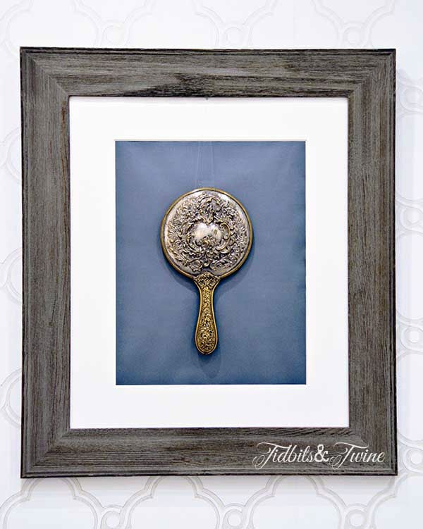 vintage silver hand mirror framed and hanging on bathroom wall