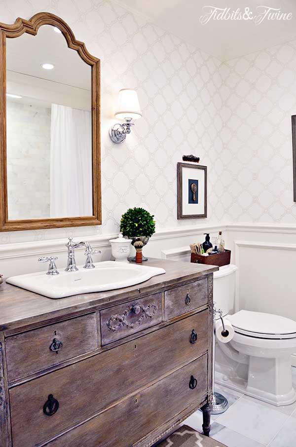 A guest bathroom transformation: from builder-grade to beautiful! Beadboard ceiling, wallpaper, sconces, marble floors, and a vanity converted from a vintage dresser!