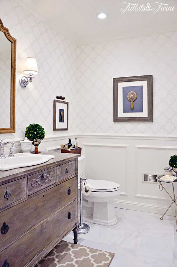 A guest bathroom transformation: from builder-grade to beautiful! Beadboard ceiling, wallpaper, sconces, marble floors, and a vanity converted from a vintage dresser!