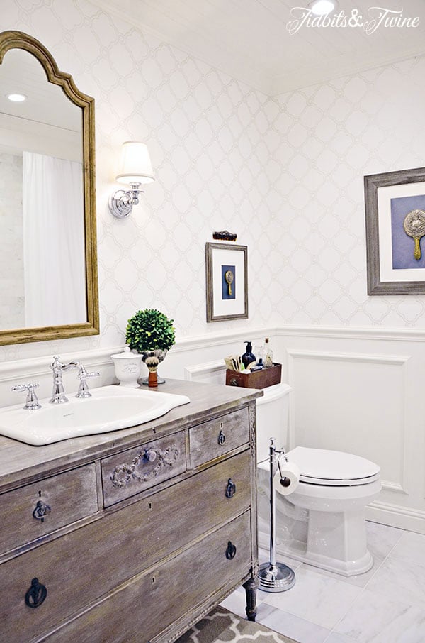 small bathroom with antique dresser used as a vanity and trellis wallpaper