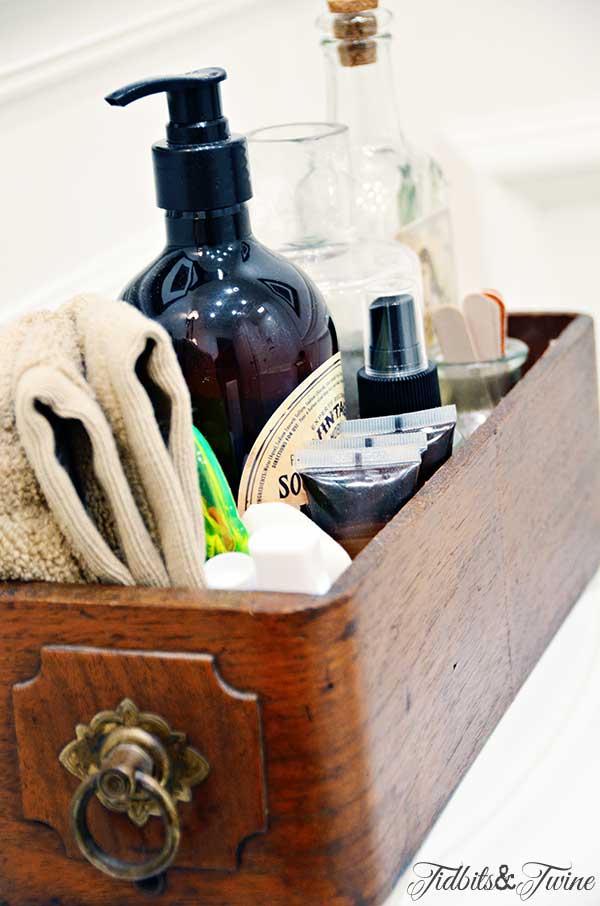 vintage sewing drawer on back of toilet holding guest bathroom essentials like shampoo toothbrush and soap