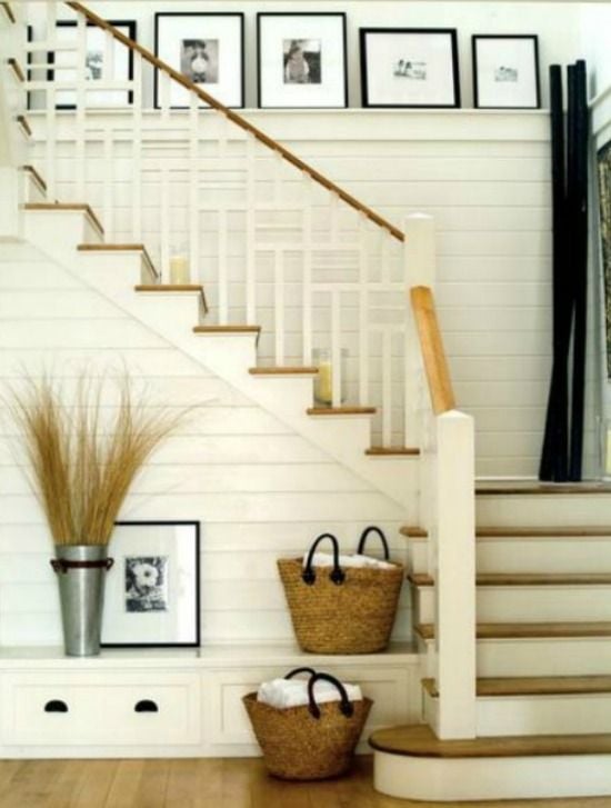 White planked staircase  wall with light wood floors and ledge that holds black and white family photos