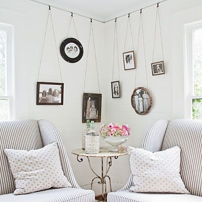 white living room with two stripped accent  chairs and table in between with art hanging from ceiling to fill empty corner