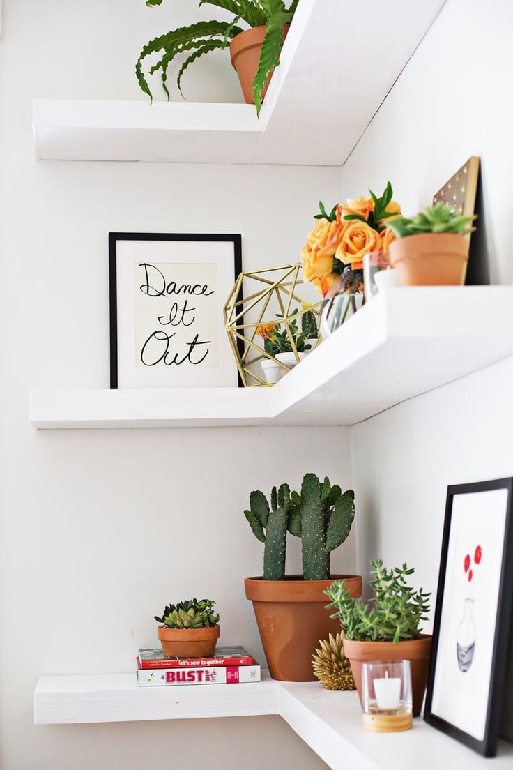 floating white corner shelves decorated with pops of orange green and gold