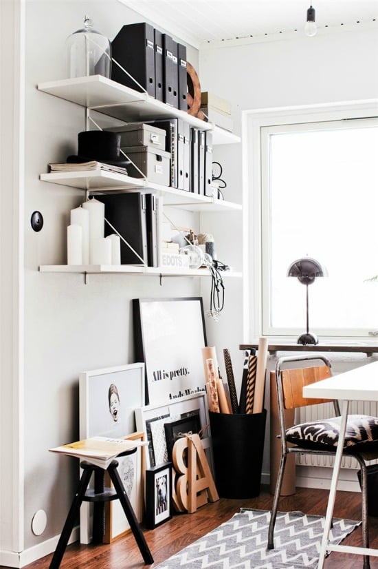 white office wall with shelves full of boxes and artwork leaned against the wall below