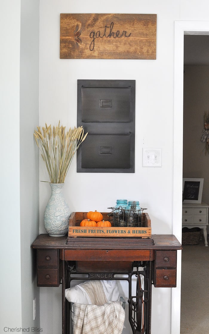 Vintage singer sewing machine in a corner with magazine rack above and antique wooden grate on top