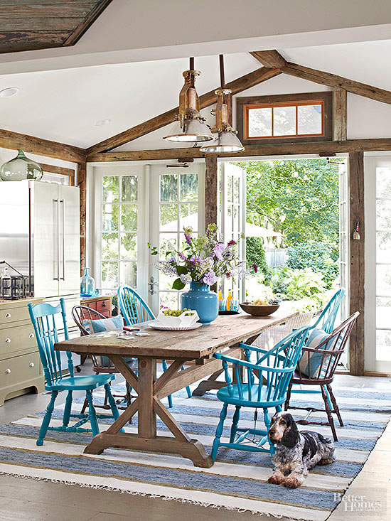 Long wooden dining table with alternating blue and brown spindle style dining chairs