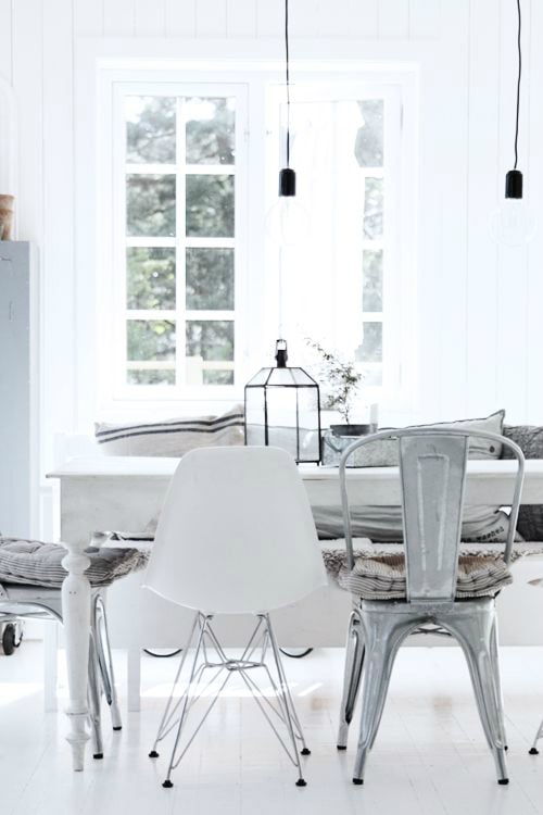 White contemporary dining room with mismatched chairs and white farmhouse table