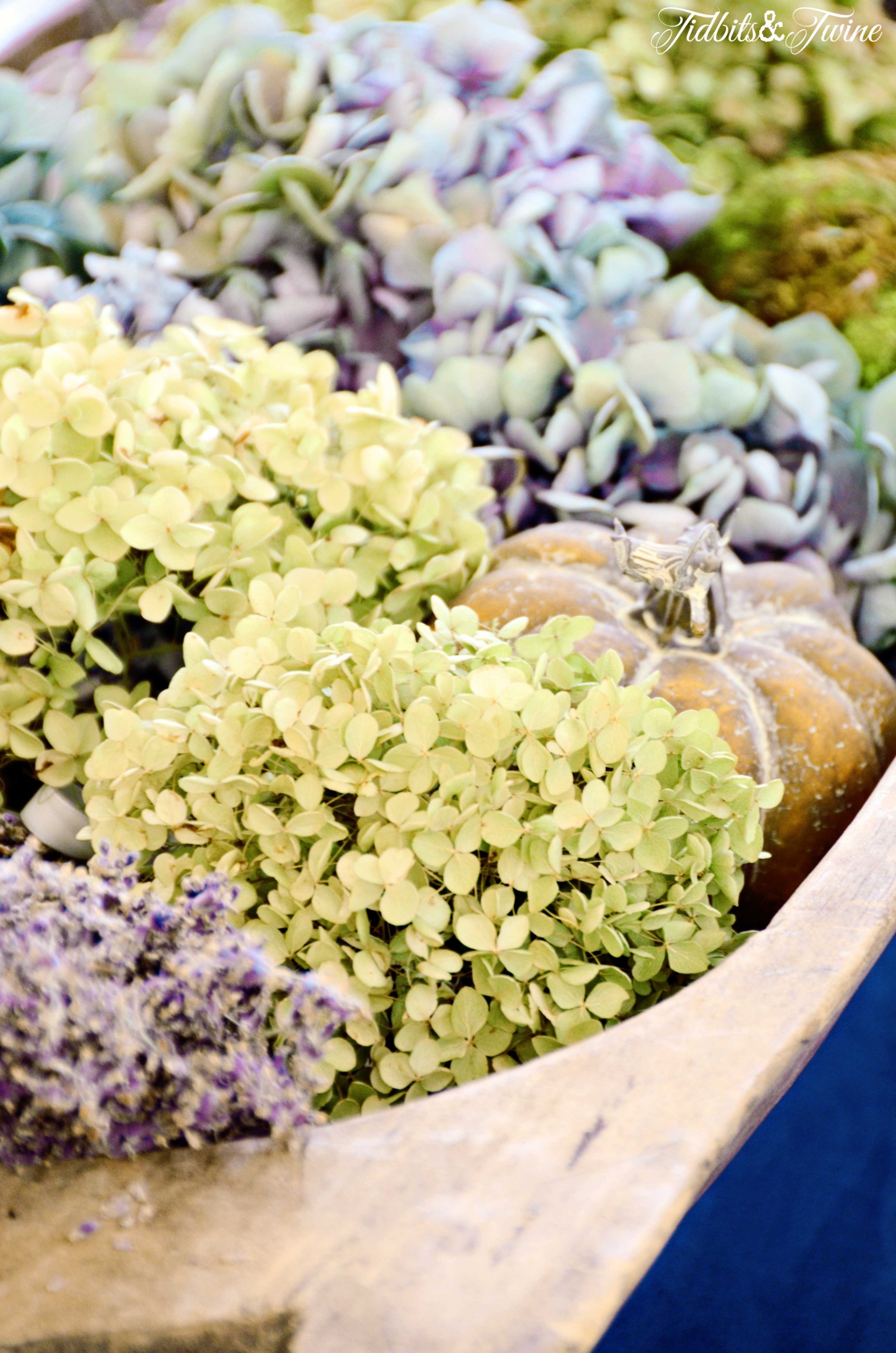 green blue and purple dried hydrangea and dried lavender with faux pumpkins in a dough bowl