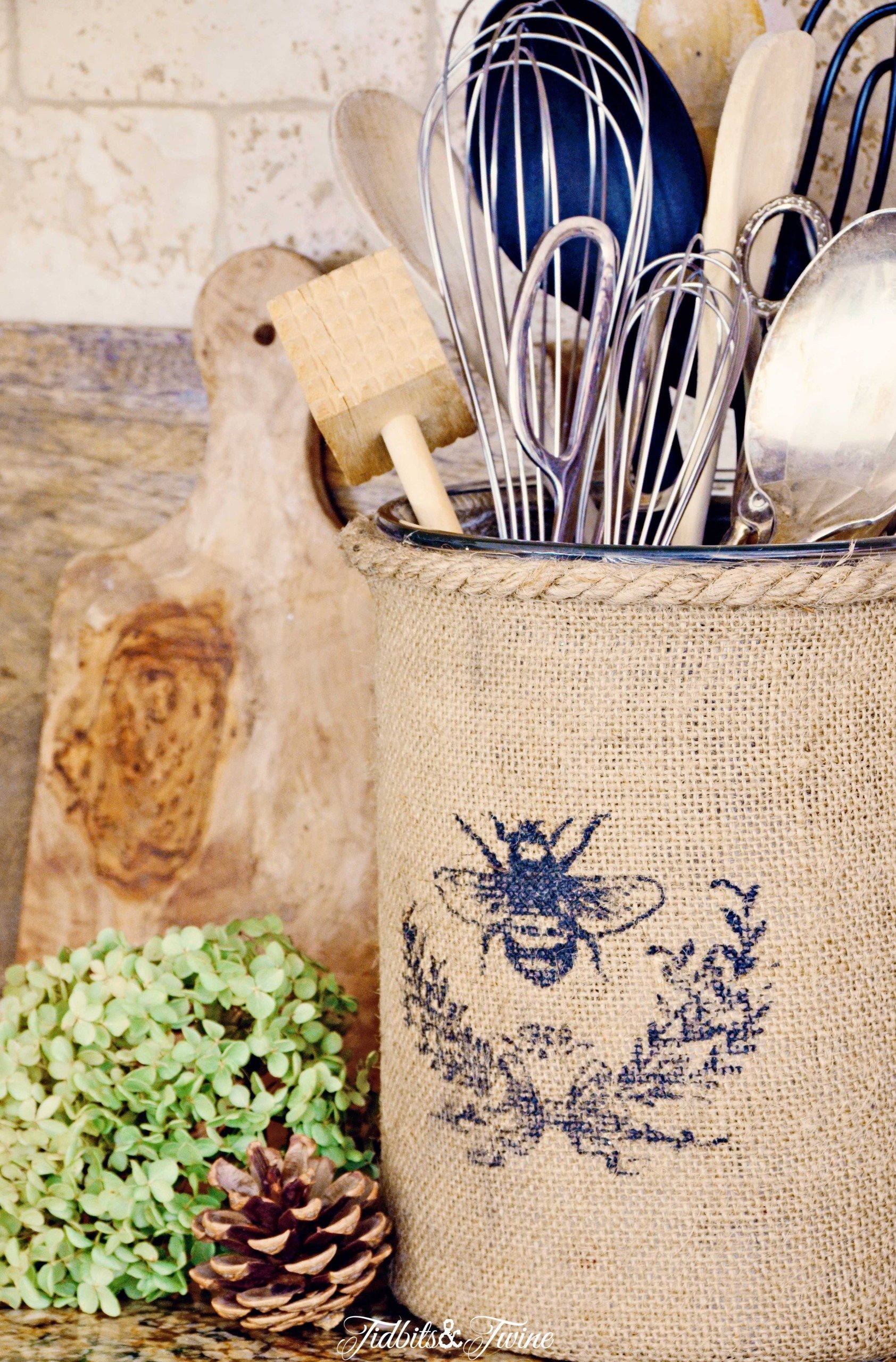 Burlap covered vase holding kitchen utensils in a French farmhouse kitchen