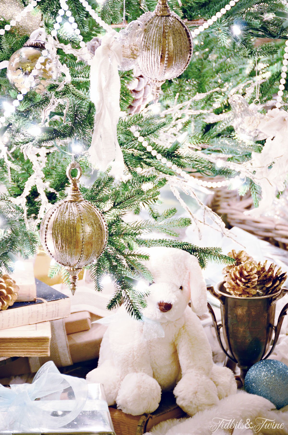 underneath a christmas tree with old books a white bear and trophy cut full of gold pinecones