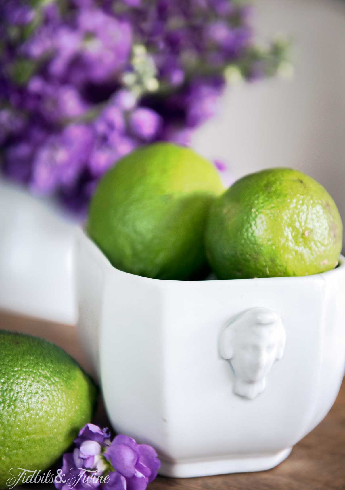 Limes in an ironstone pot with purple flowers for dining room centerpiece