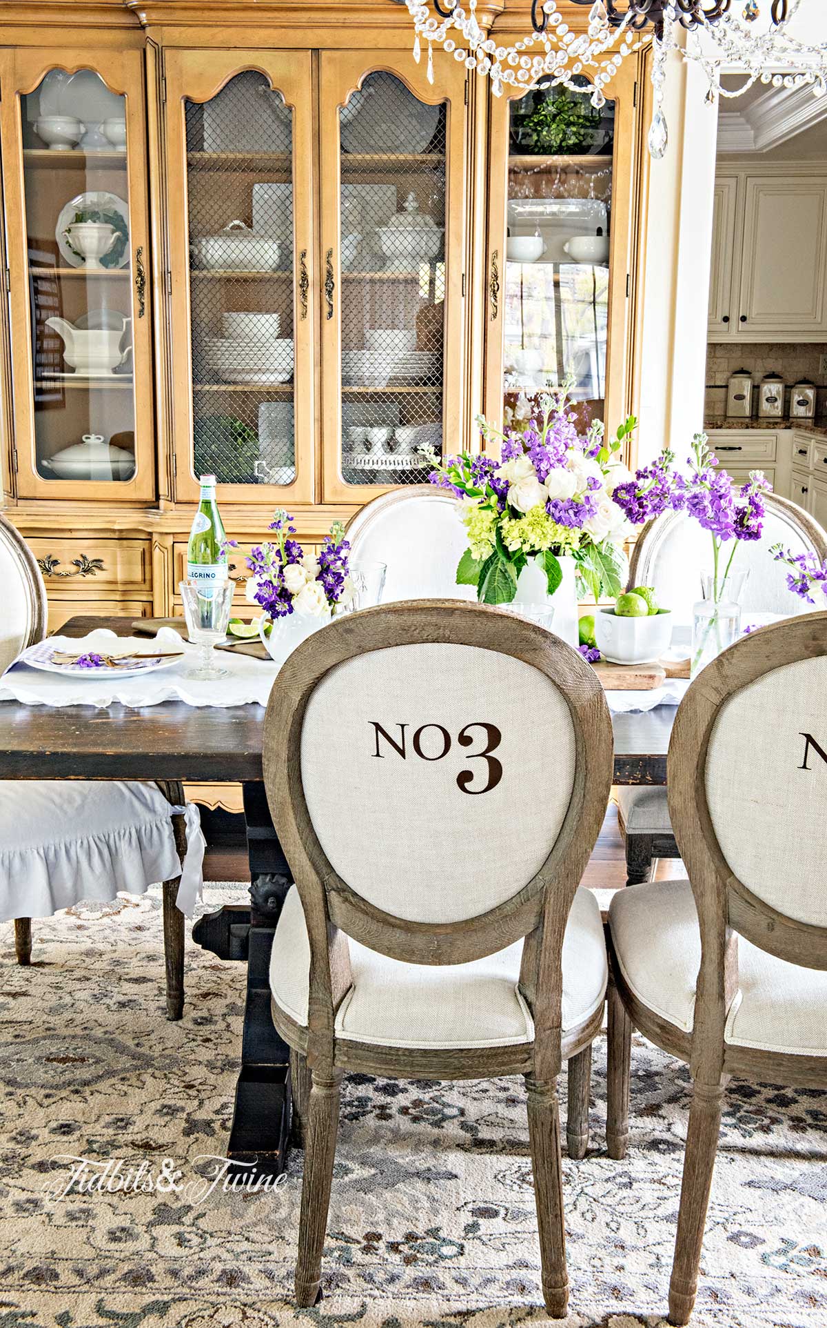 spring tablescape in french dining room with numbered chairs and crystal chandelier