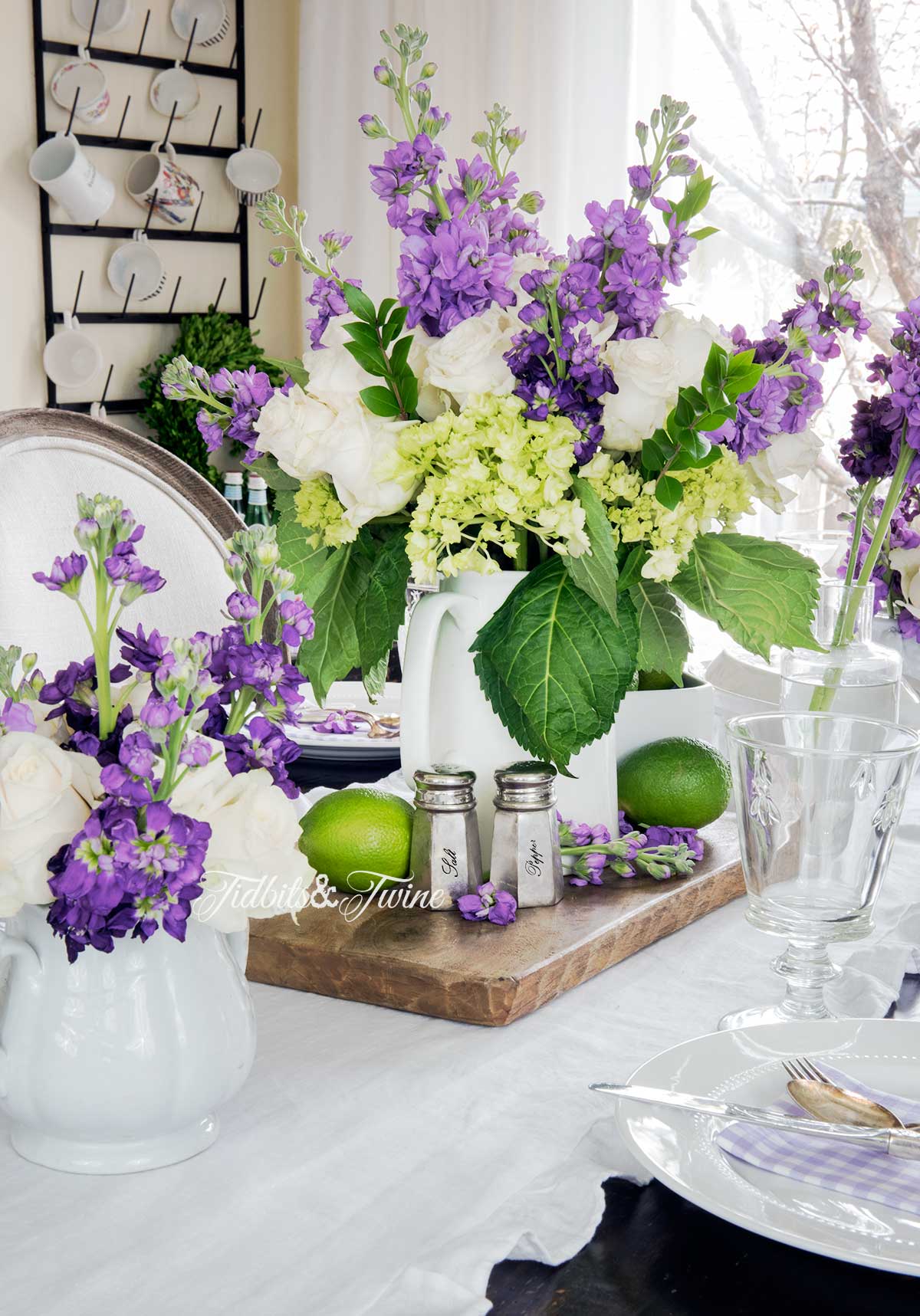 Purple white and green flower centerpiece on a bread board with limes