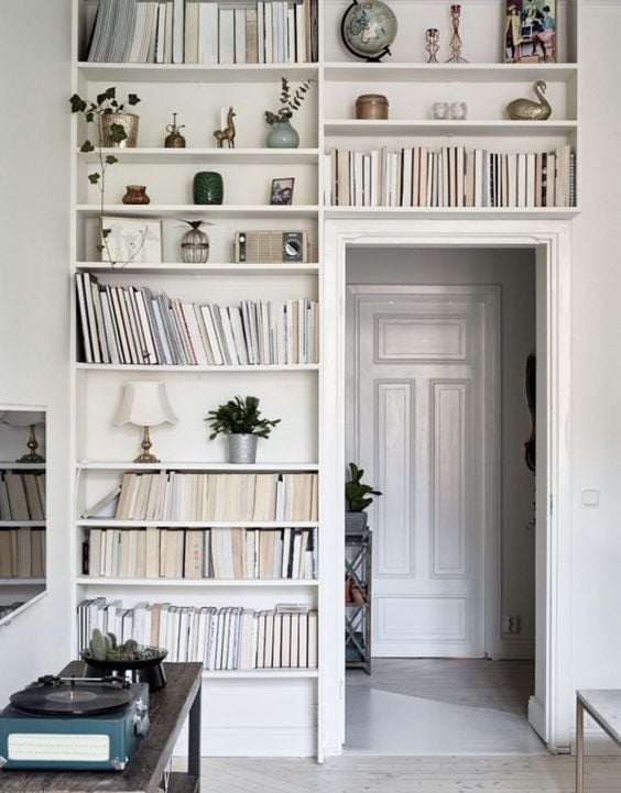 White built in shelves filled with books that surround a doorway