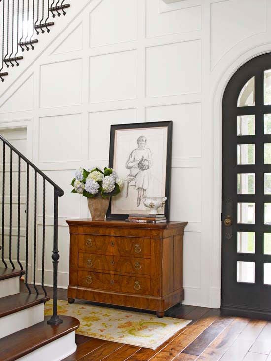 White board and batten wall trim in an entryway with a small decorative dresser and artwork