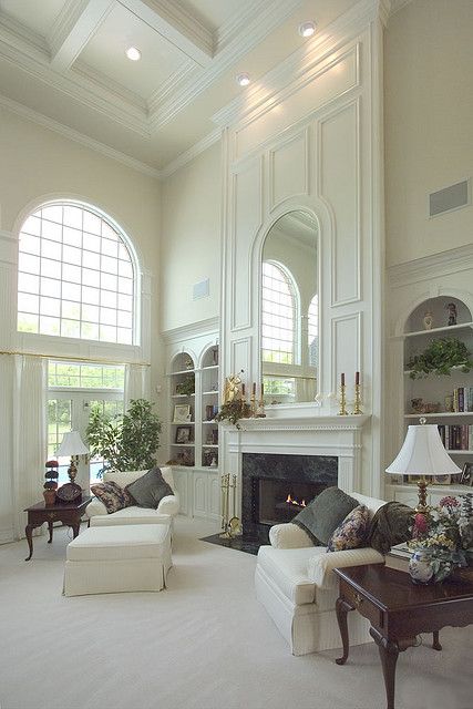 Vaulted living room with white molding above fireplace and built in bookcases on sides