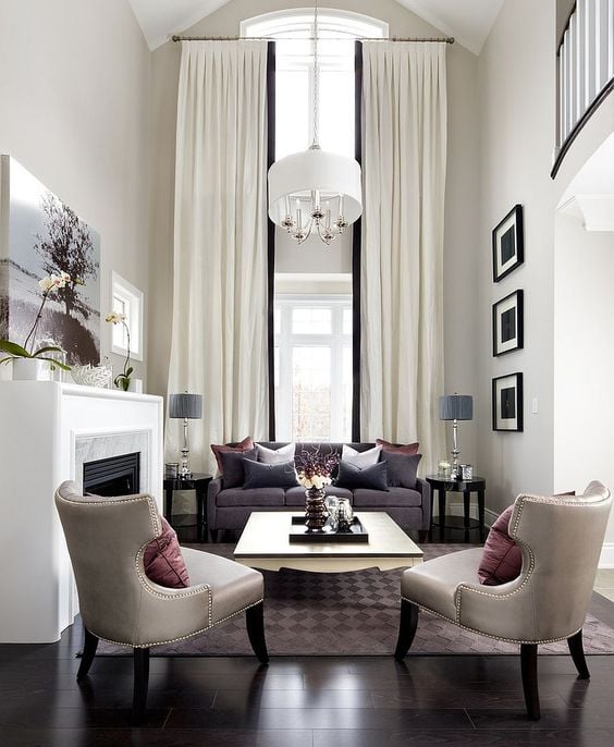 Contemporary living room with vaulted ceiling and white drapes with black trim on windows