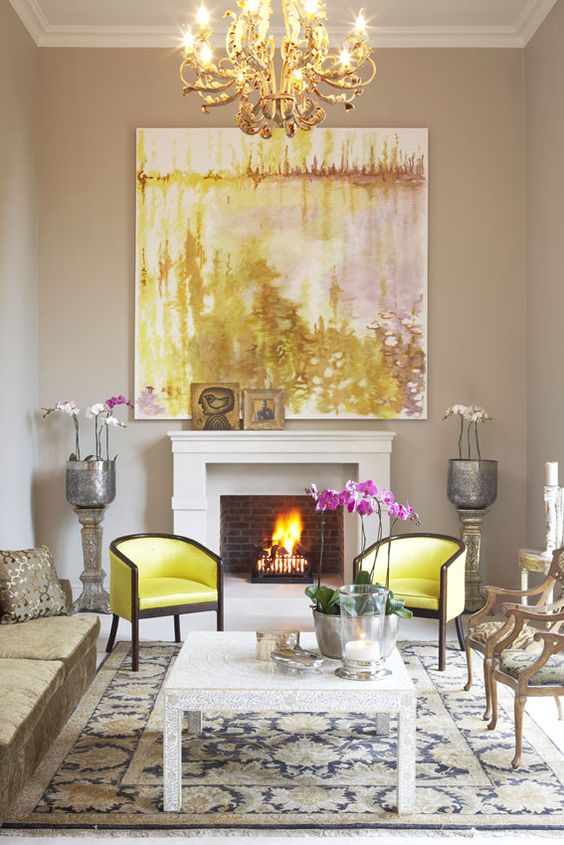 Pink and yellow oversized art canvas above a white fireplace with two yellow chairs in front